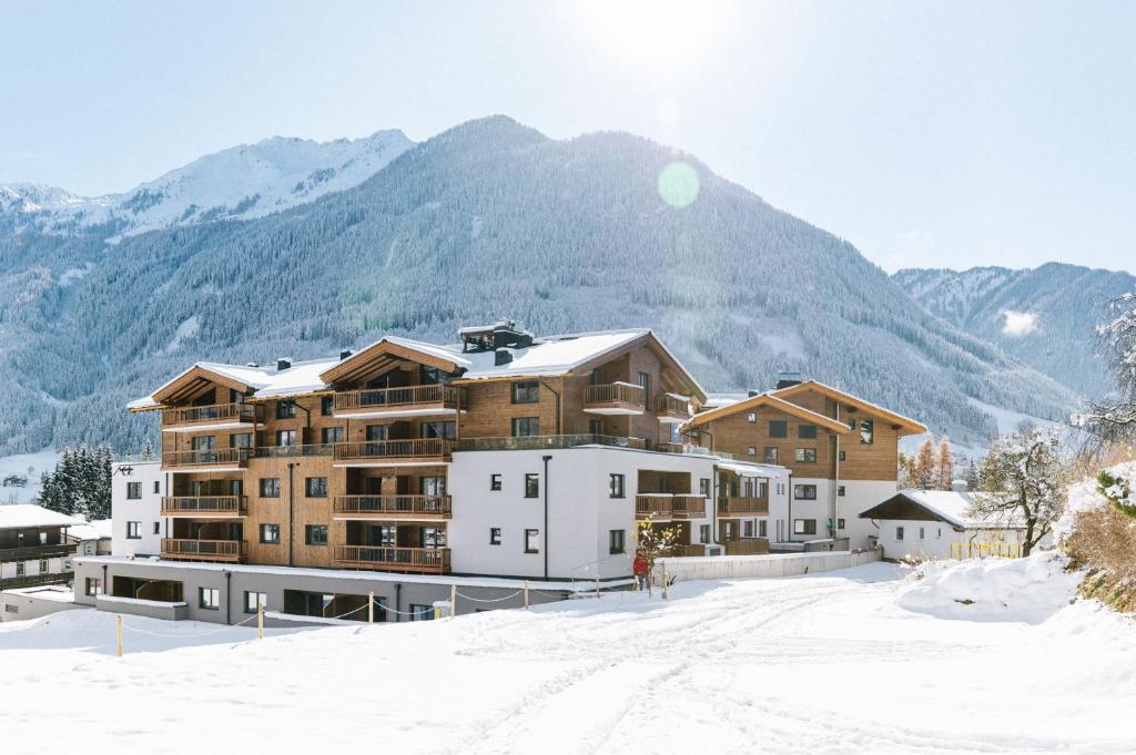ein großes Gebäude im Schnee mit einem Berg in der Unterkunft Venediger Lodge in Neukirchen am Großvenediger