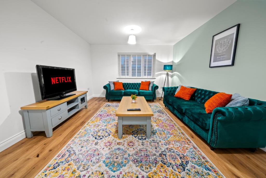 a living room with a green couch and a tv at AltoHaus Luxury 4BR House By AltoLuxo Short Lets & Serviced Accommodation With Parking in Bristol