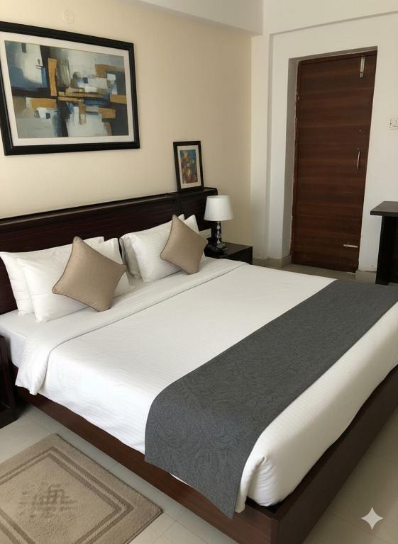 a bedroom with a large bed with white sheets and pillows at Govinda Hall in Kānpur