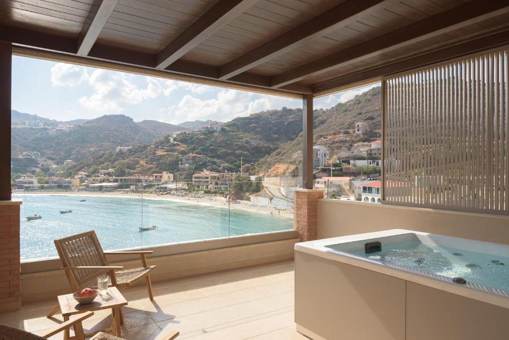 a room with a tub and a view of a beach at Nere Suites in Lygaria