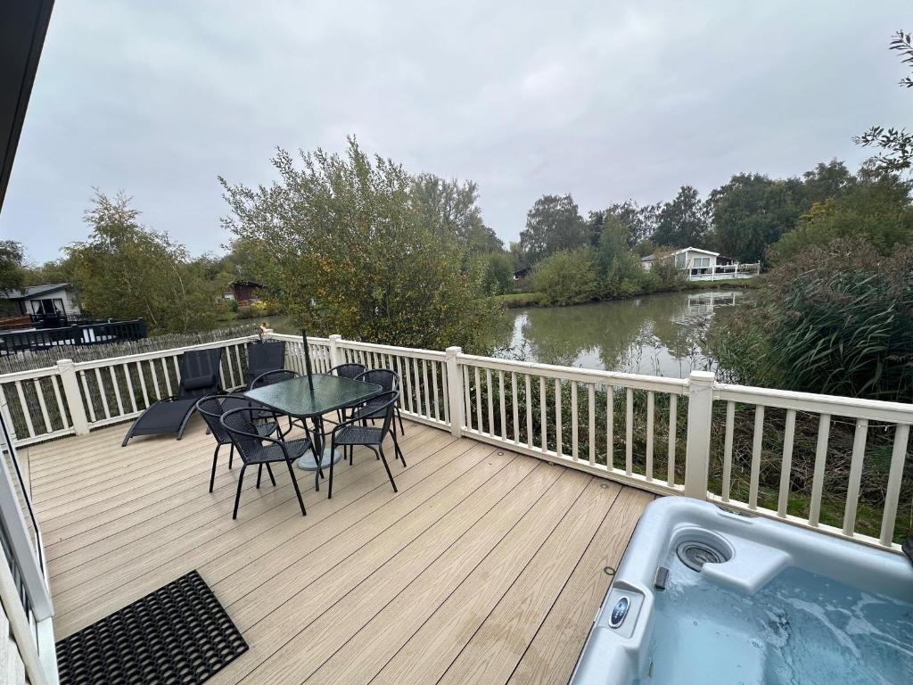 a deck with a table and chairs and a bath tub at Luxury Lakeside Lodge L2 with Hot tub situated at Tattershall Lakes Country Park in Tattershall