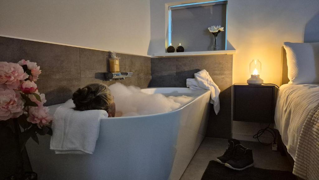 a woman sitting in a bath tub in a bedroom at Dalerheugte Wellness B&B in Dalerveen