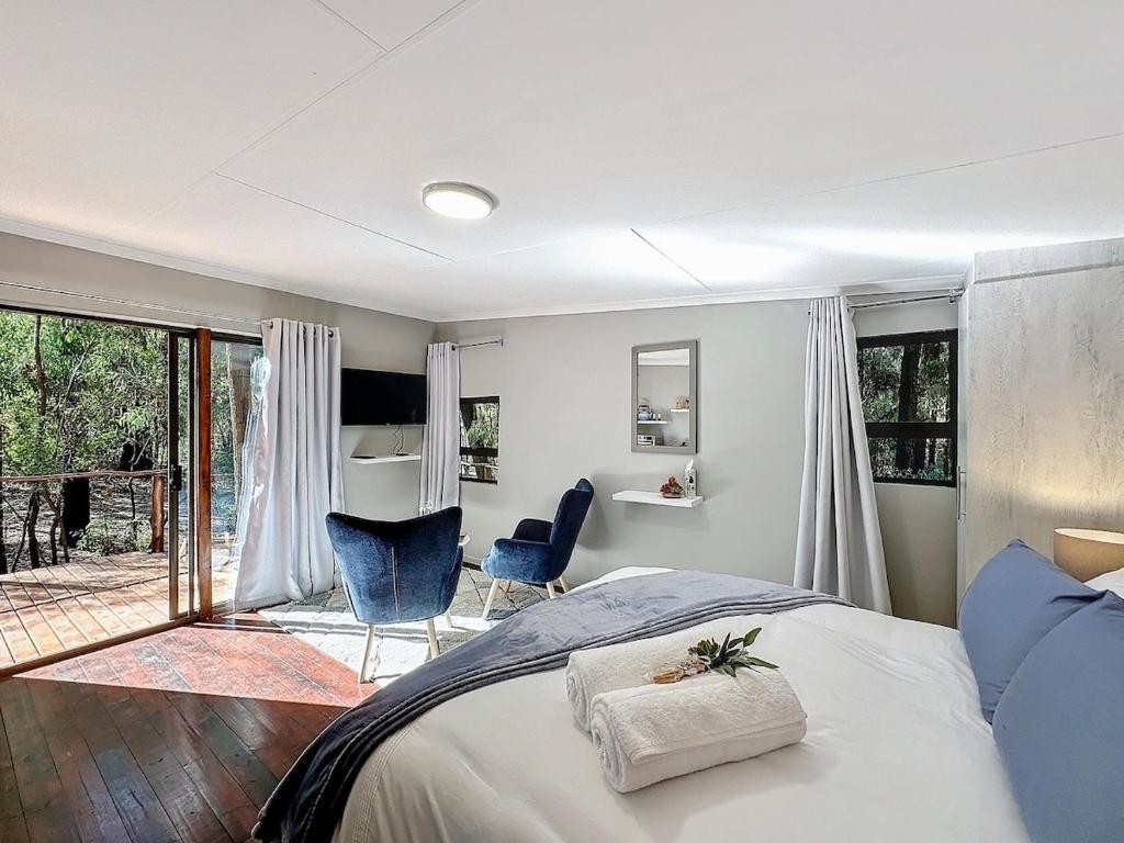 a bedroom with a bed and two chairs and a patio at Luxury Tranquil Treehouse & Hot Tub in Pretoria