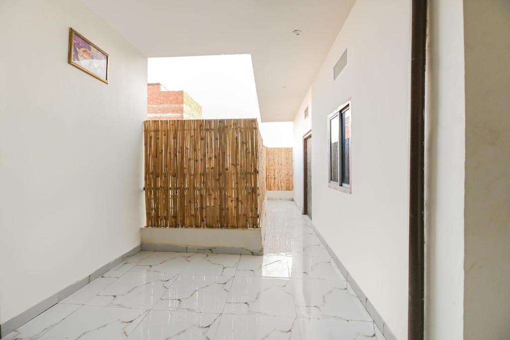 un couloir avec des murs blancs et une porte en bois dans l'établissement Hotel O Tara Mahal, à Jaipur