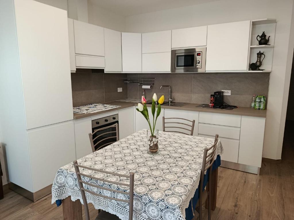 Una cocina con una mesa con un jarrón de flores encima. en Casa Vacanze Da Anna, en Grosio