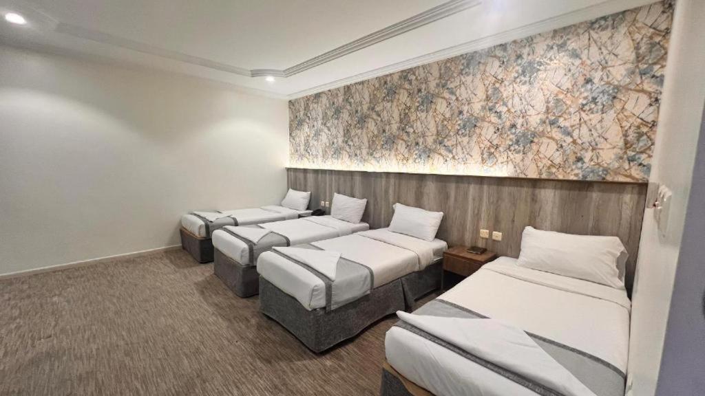 a room with three beds and a painting on the wall at فندق الخلفاء الفيصلية الفندقية in Makkah