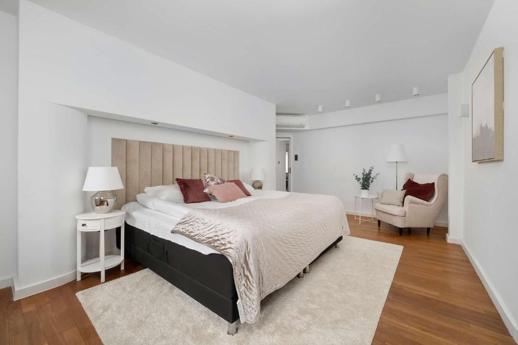 a white bedroom with a large bed and a chair at Family Apartment with 3 Bedrooms & Air Conditioning in the Centre of Wrocław by Noclegi Renters in Wrocław