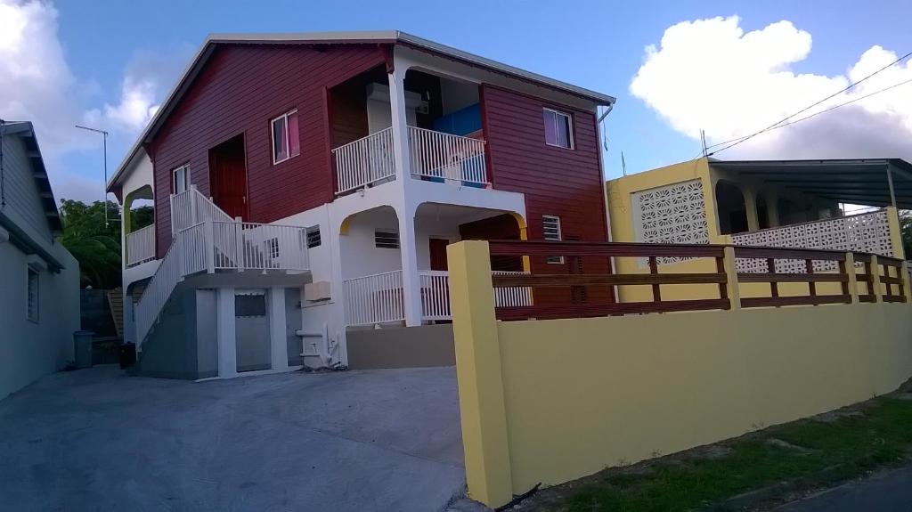 una casa roja y blanca con una valla de madera en Résidence PATROS, en Sainte-Anne