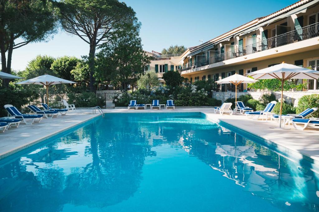 ColomarsにあるAuberge du Rédier - Logis Hôtelsのホテルの隣にあるスイミングプール(椅子、パラソル付)
