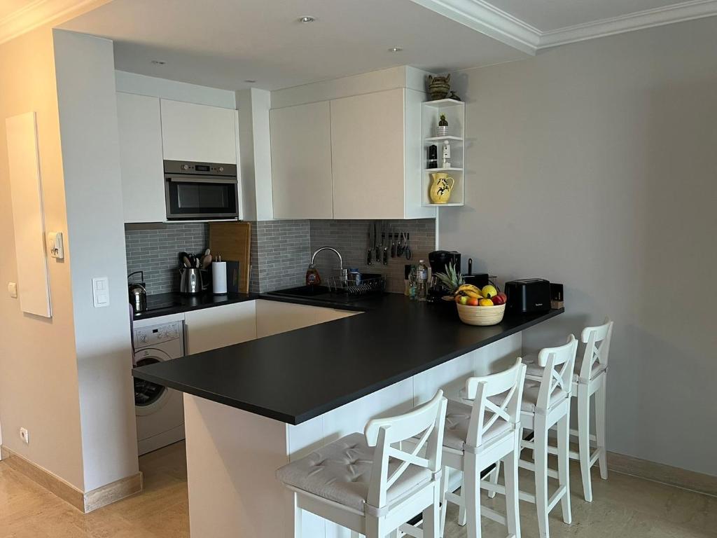 a kitchen with a black counter top and white cabinets at Le Lido - Piscine, proche plage in Cros-de-Cagnes