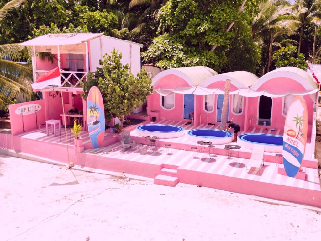 une maison rose avec deux piscines et des parasols dans l'établissement Noel Cottage, à Ngurblut
