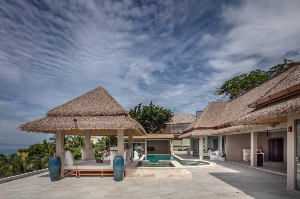 a resort with a pool and a straw umbrella at Villanirvanasamui 