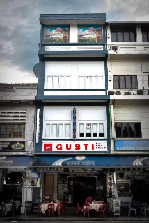 a tall white building with a restaurant in front of it at GUSTI Backpackers Capsule Hostel Singapore in Singapore
