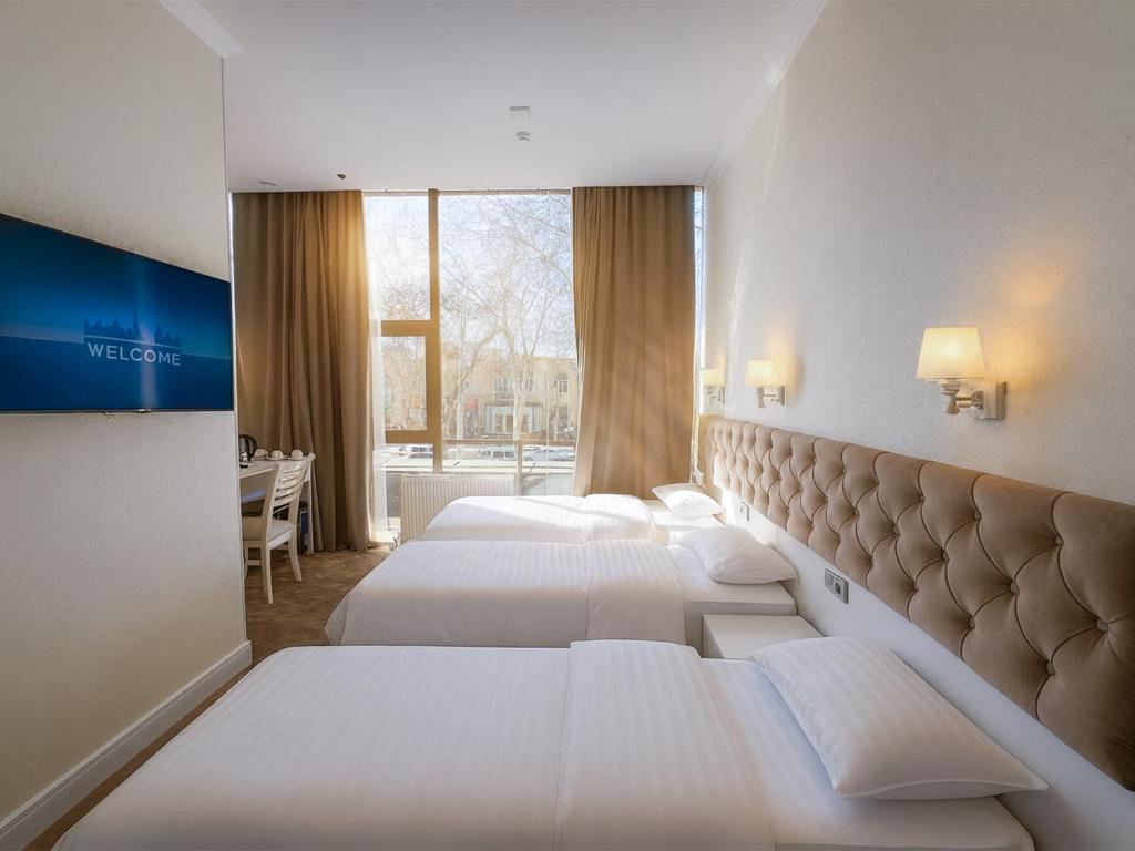 a hotel room with two beds and a window at Panorama Hotel & More in Samarkand