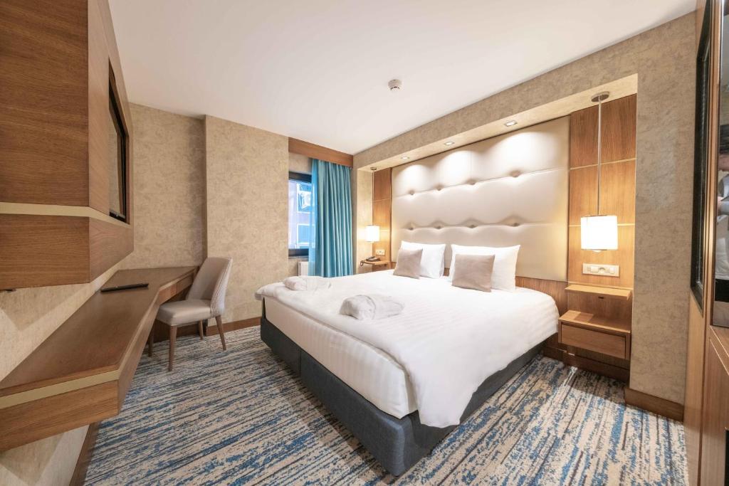 Una habitación de hotel con una cama grande y un escritorio. en Grand Canyon Hotel, en Ankara
