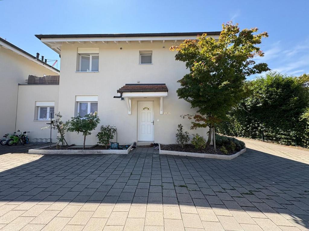 a white house with a white door and a tree at Charming family villa in Geneva