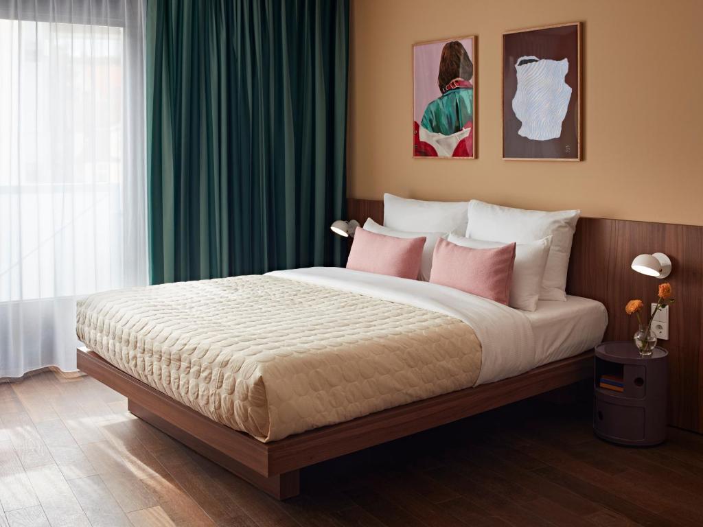 a bedroom with a large bed with green curtains at Numa Stuttgart Rotebühlplatz in Stuttgart
