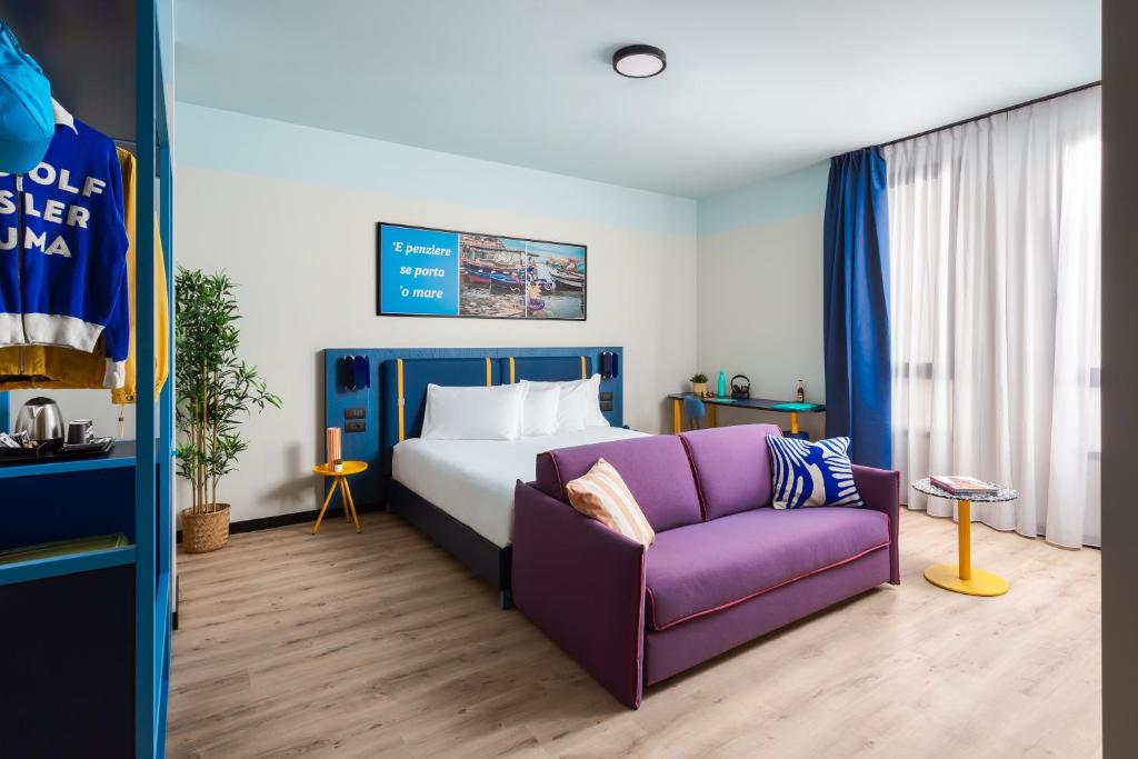 um quarto com uma cama e um sofá roxo em CX Naples Centrale em Nápoles