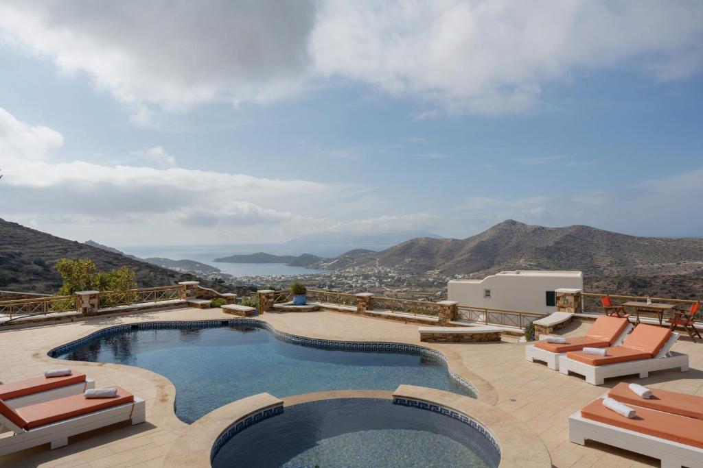 a pool with chairs and a view of the mountains at Aegean Villas Ios in Ios Chora