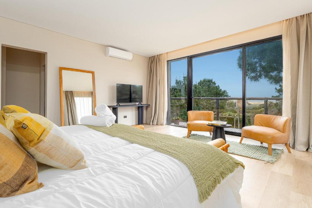 a bedroom with a large bed and a large window at Kemay Hotel Boutique in José Ignacio