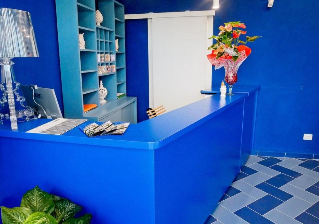 Cette chambre bleue comprend un bureau avec un vase de fleurs. dans l'établissement villa oltremare resort, à Bagheria