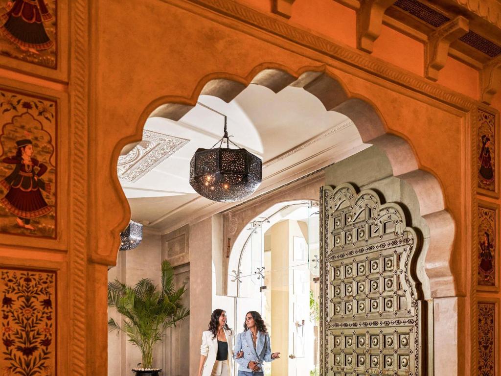 two women walking through a hallway in a building at Fairmont Jaipur in Jaipur