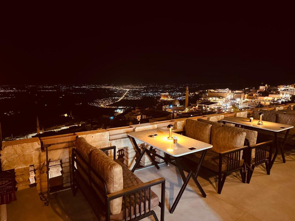 ein Restaurant mit Tischen und Stühlen auf einem Balkon bei Nacht in der Unterkunft Kadim Hotel in Mardin
