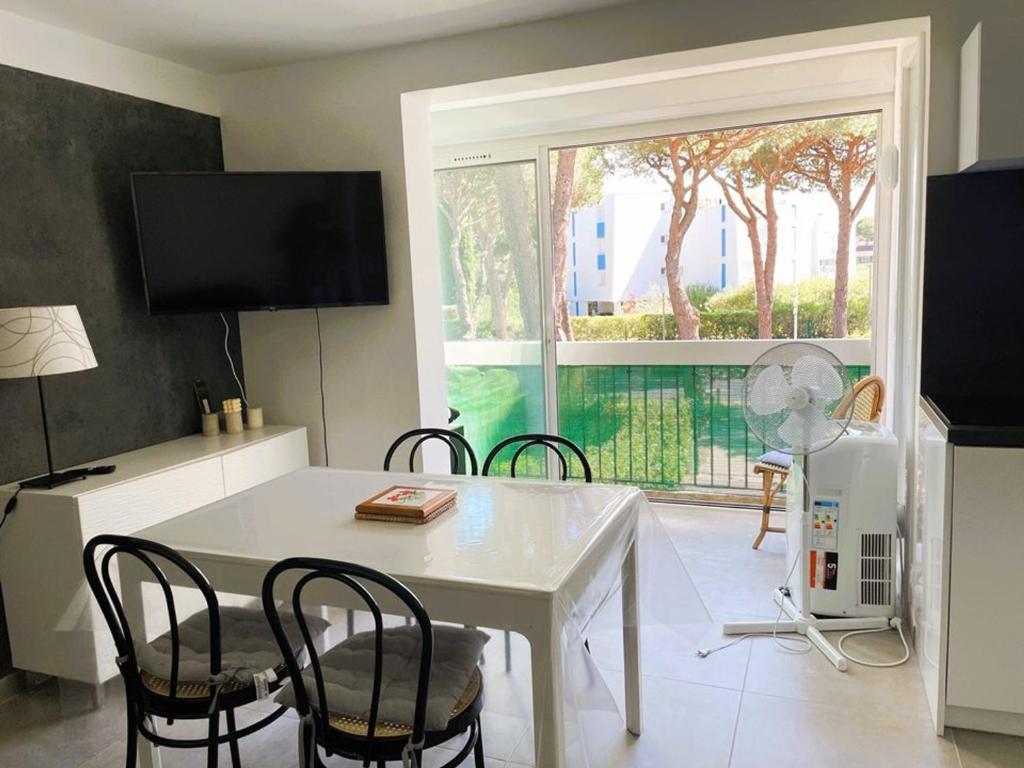 a dining room with a white table and chairs and a window at La Grande Motte: Appart 2 pièces lumineux, 4 couchages, parking privé - FR-1-790-35 in La Grande-Motte