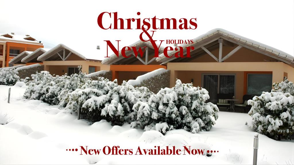un panneau de Noël et du Nouvel An devant une maison couverte de neige dans l'établissement Litohoro Olympus Resort Villas & Spa, à Plaka Litochorou