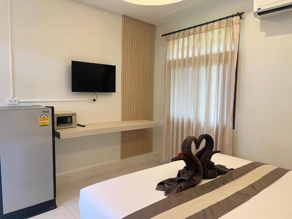 a room with a bed with a tv on the wall at Prukrom Lanta Guesthouse in Ko Lanta