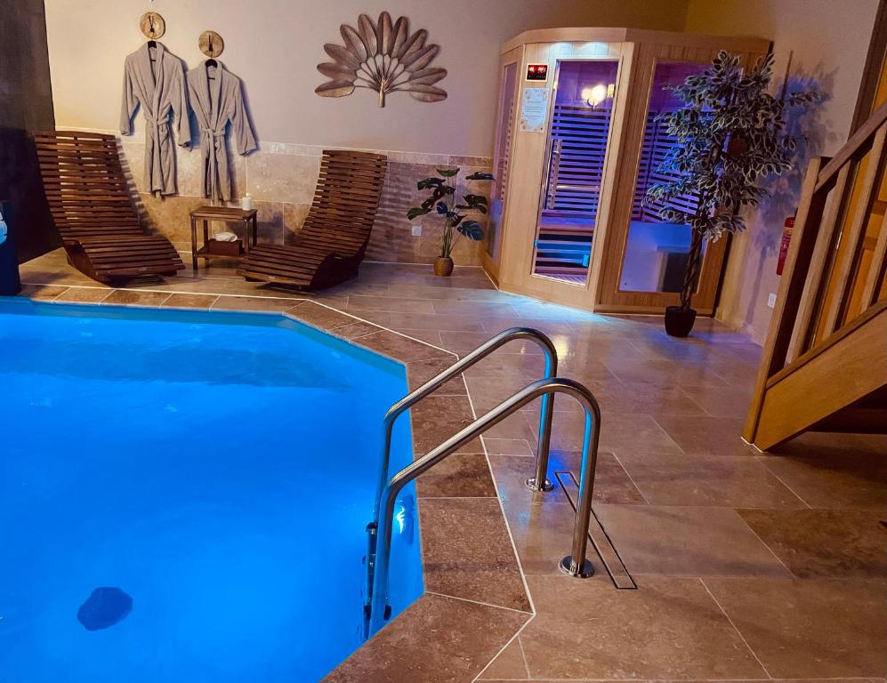 a large swimming pool in a room with chairs at Evaziona in Blairville