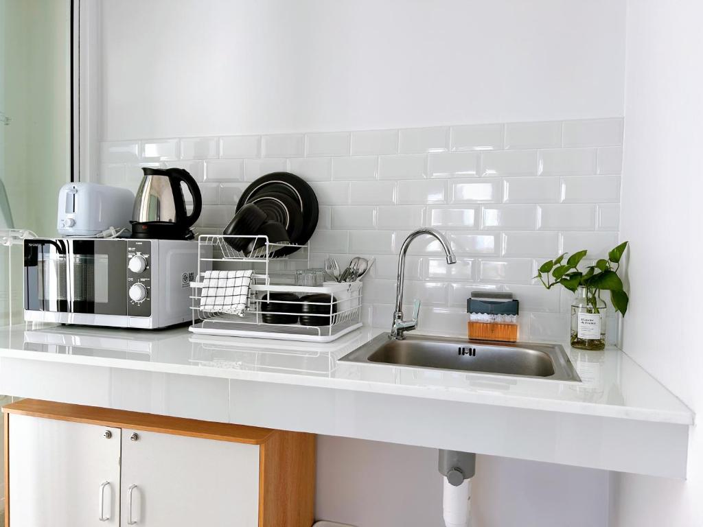 a kitchen counter with a sink and a microwave at Komfy Quarters in Sathani Bang Khen