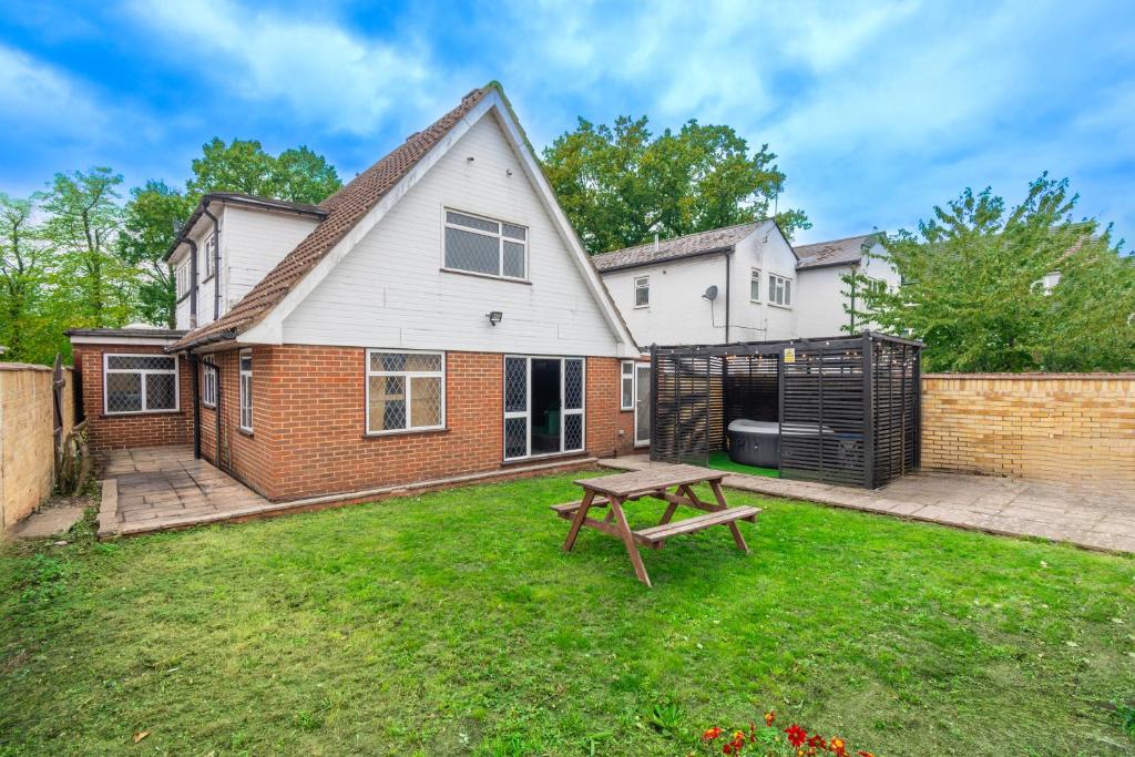 a house with a picnic table in the yard at Slough Fun Home with Hot tub, Cine, Garden & Parking in Colnbrook