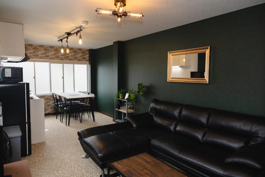a living room with a black leather couch and a table at Darin博多 in Fukuoka