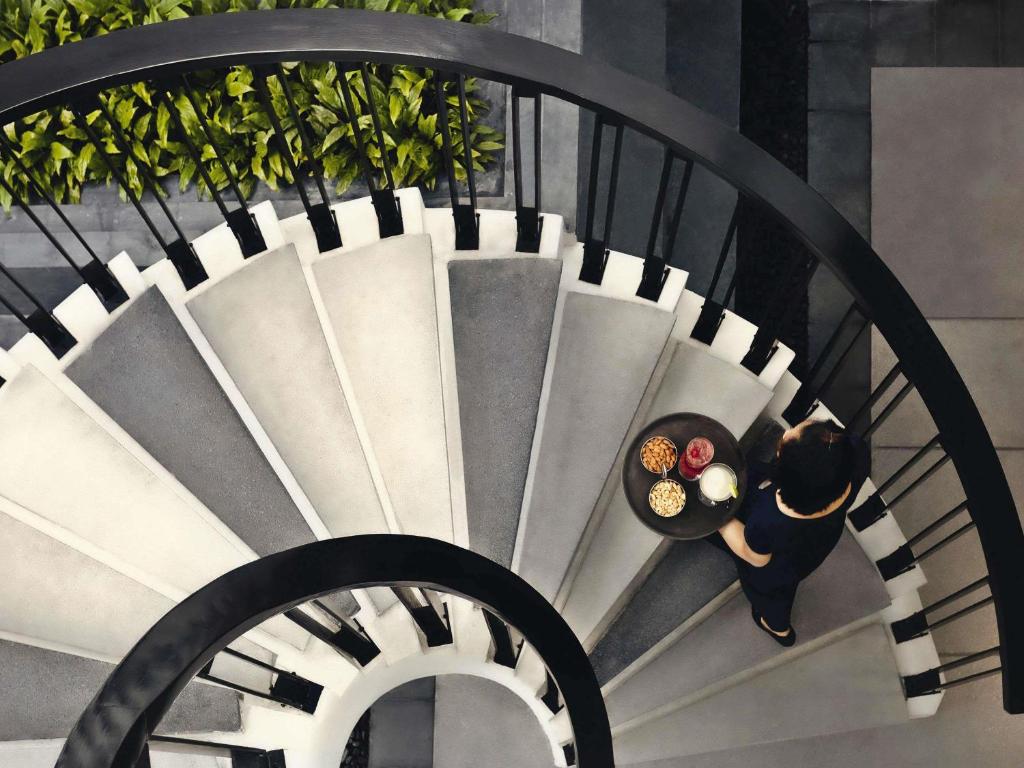 a woman is walking down a spiral staircase at Mövenpick Hotel Sukhumvit 15 Bangkok in Bangkok