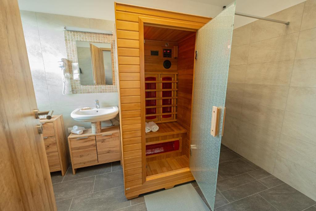 a bathroom with a sink and a glass shower door at ARKSIS Apartman in Sárvár