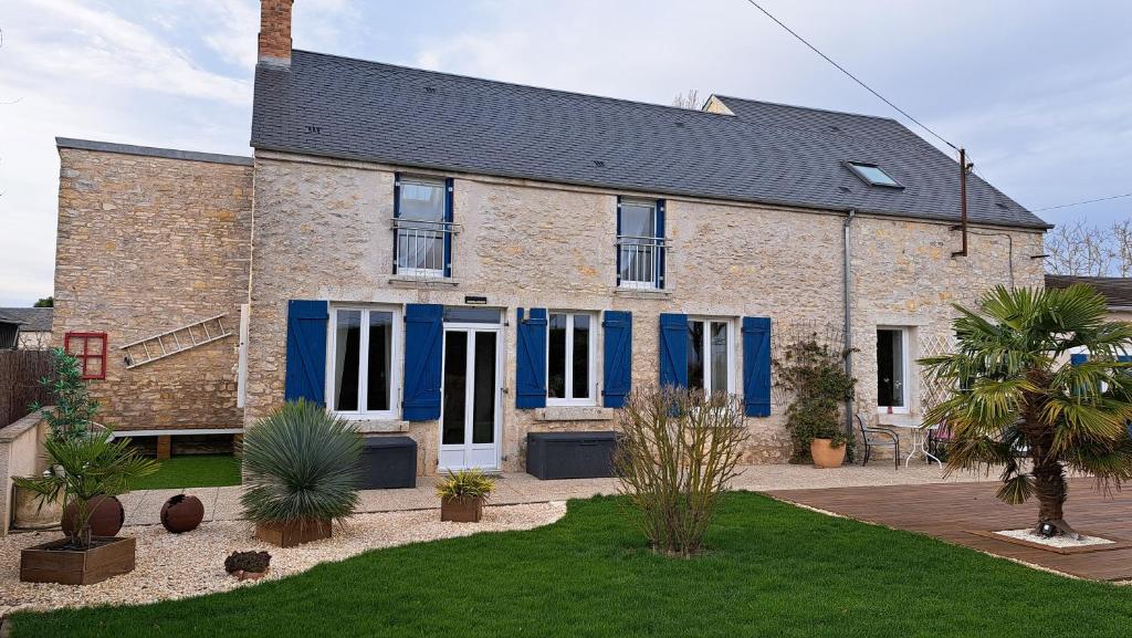 a brick house with blue shutters and a yard at Halte détente chez Sylvie près A71 Bourges - chambres avec sauna, billard, salle ciné in Civray
