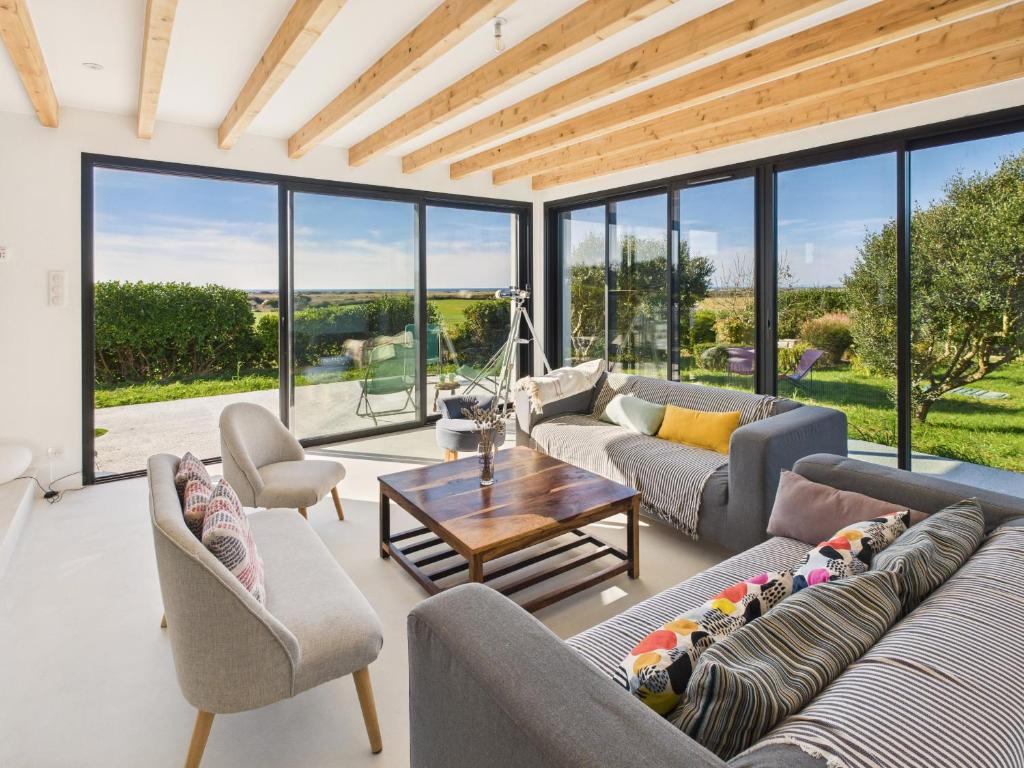 a living room with couches and a table and windows at Longère - 10 personnes - Vue mer in Tréguennec