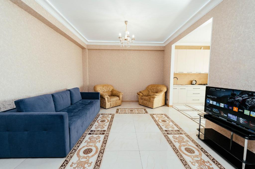 un soggiorno con un divano blu e una TV di Apartment ultra center Sky House a Chişinău