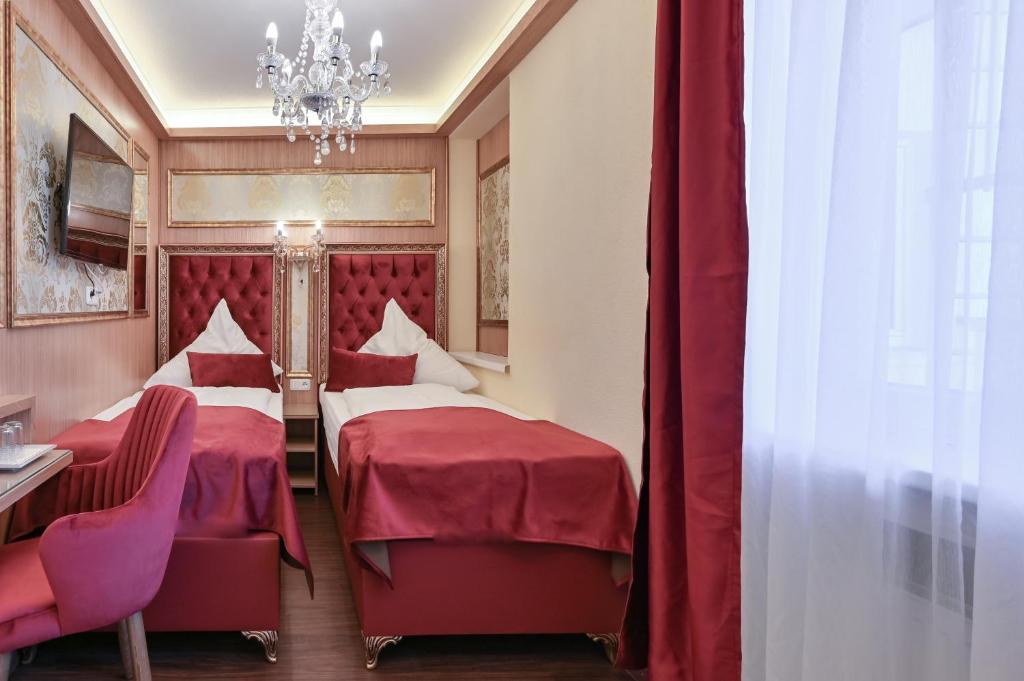 a hotel room with two beds and a chandelier at Hotel Ludwigs in Füssen