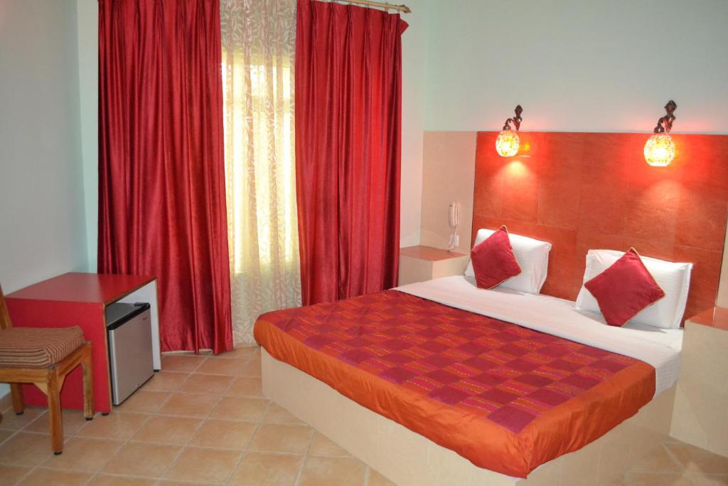 a bedroom with a large bed and red curtains at Ray of Maya in Agra