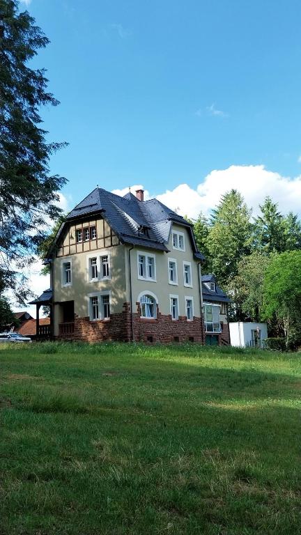 a large house on a grassy field with trees at Forsthaus Hausbach - Ferienwohnung Hirsch in Losheim
