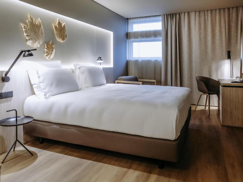Una habitación de hotel con una cama grande y un escritorio. en Mercure Fátima, en Fátima