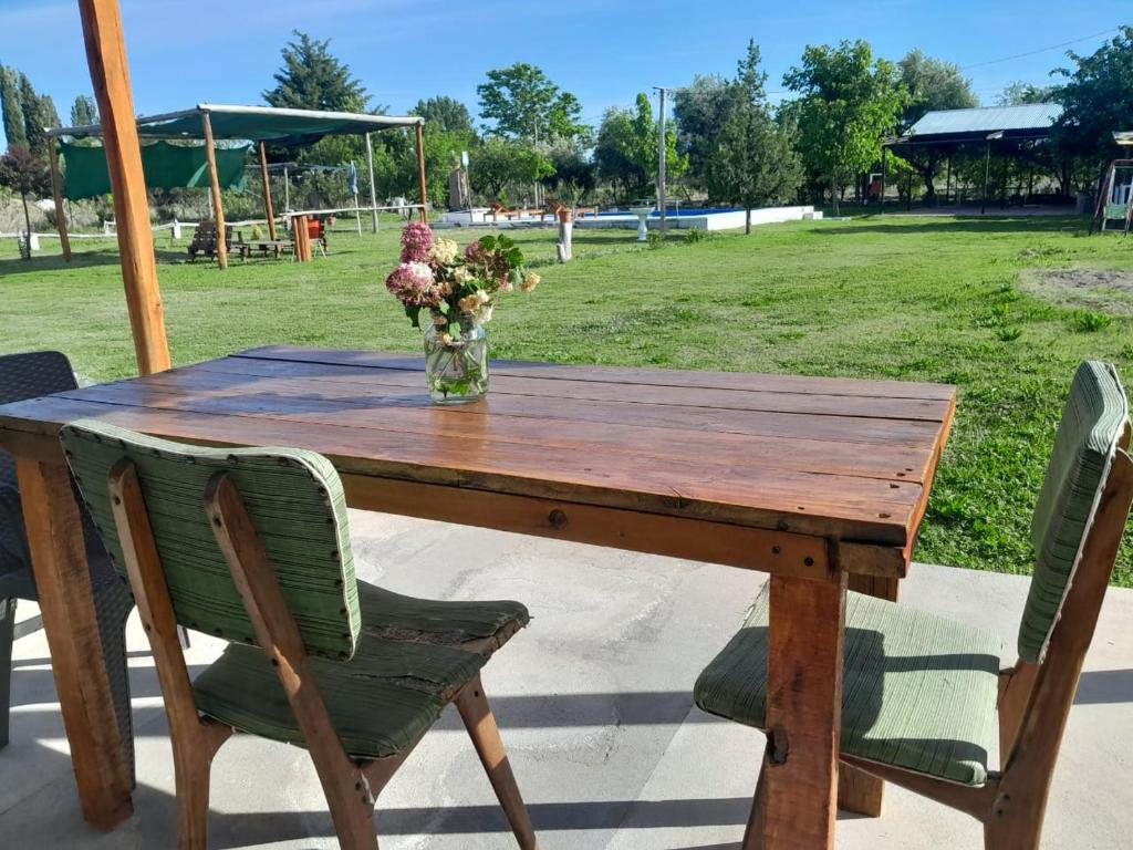 een houten tafel met een vaas met bloemen erop bij Cabaña LuMa in San Rafael
