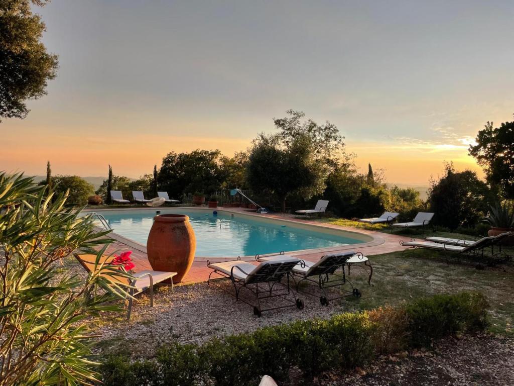 a swimming pool with chairs and a vase next to it at Poggio Bernone - Massa Marittima in Prata