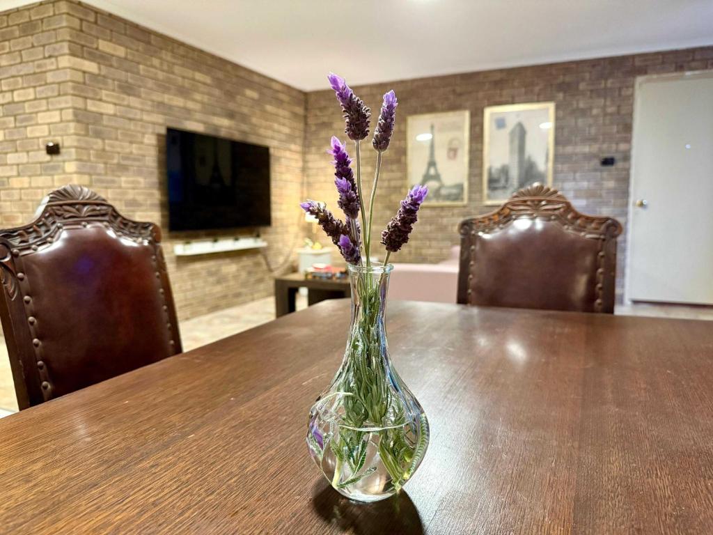 a glass vase with purple flowers in it on a table at Tweebine Villas in Utakarra