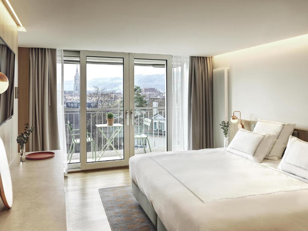 a bedroom with a large white bed and a balcony at Swissôtel Kursaal Bern in Bern
