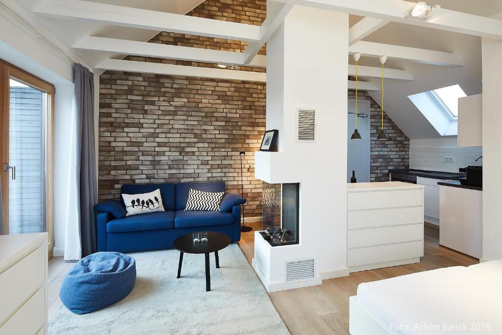 een woonkamer met een blauwe bank en een bakstenen muur bij Sylt Lofts in Westerland