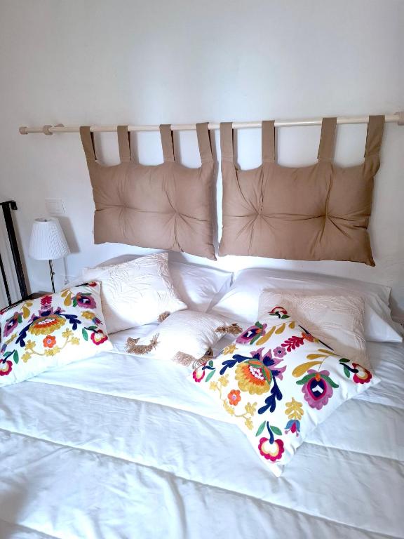 a white bed with two pillows with flowers on it at Romantic House in Trevignano Romano