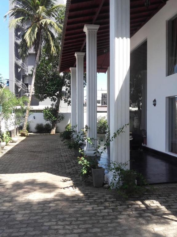 un edificio con colonne e un cortile con una palma di The Kingston Hotel a Kiribathgoda